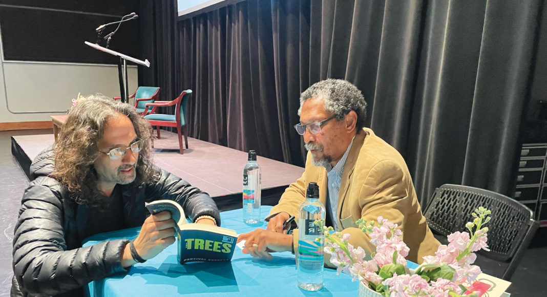 Two men seated at a table looking at a book