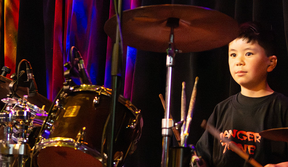 Young boy sitting behind a drum kit