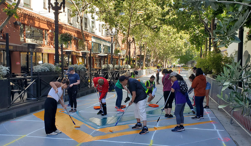 People applying colored paints to a city street