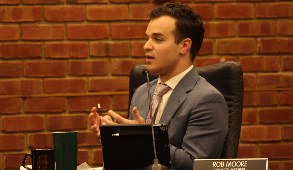 Man in profile sitting at a desk, looking at someone off camera