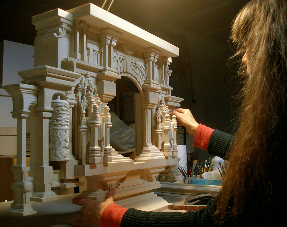 Artist Holly Lane in profile, working on a large carved frame