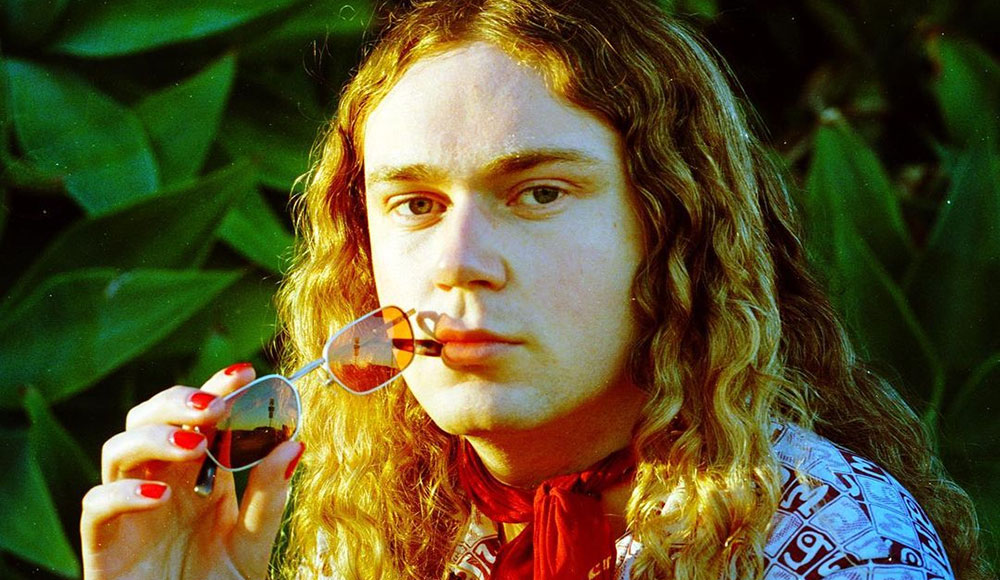 Young redheaded man with eyeglasses held up to his lips