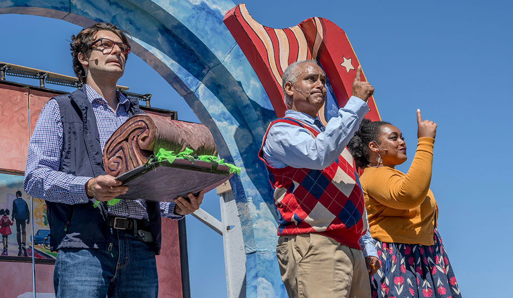 Three actors performing on an outdoor stage