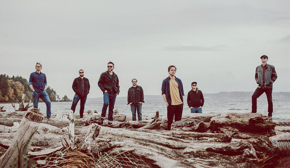 Seven people standing spaced out from each other at a beach
