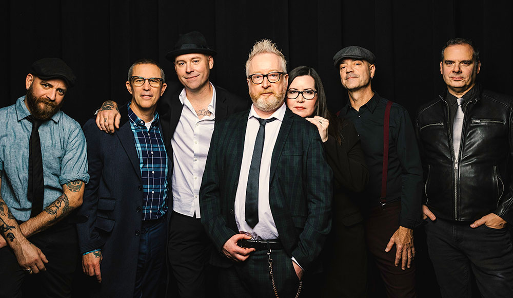 Seven people standing against a black background