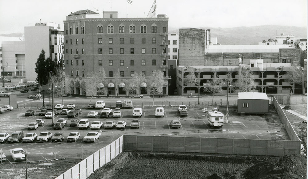Black and white photo of parking lot in front of an old hotel