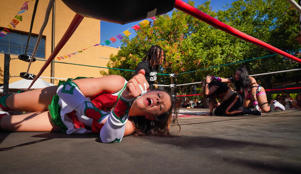 Wrestler lying down on the mat, hand outstretched and eyes closed