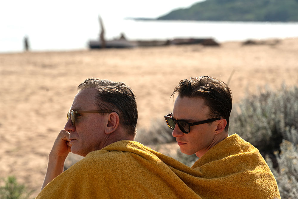 Two men outside looking at the ocean, a blanket wrapped around their shoulders