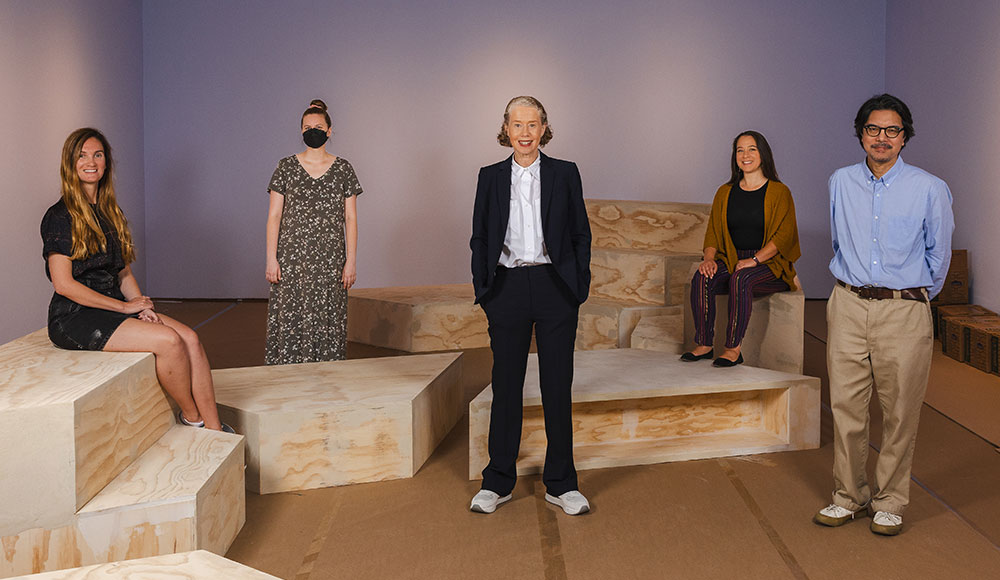 Five people standing in a sparse room