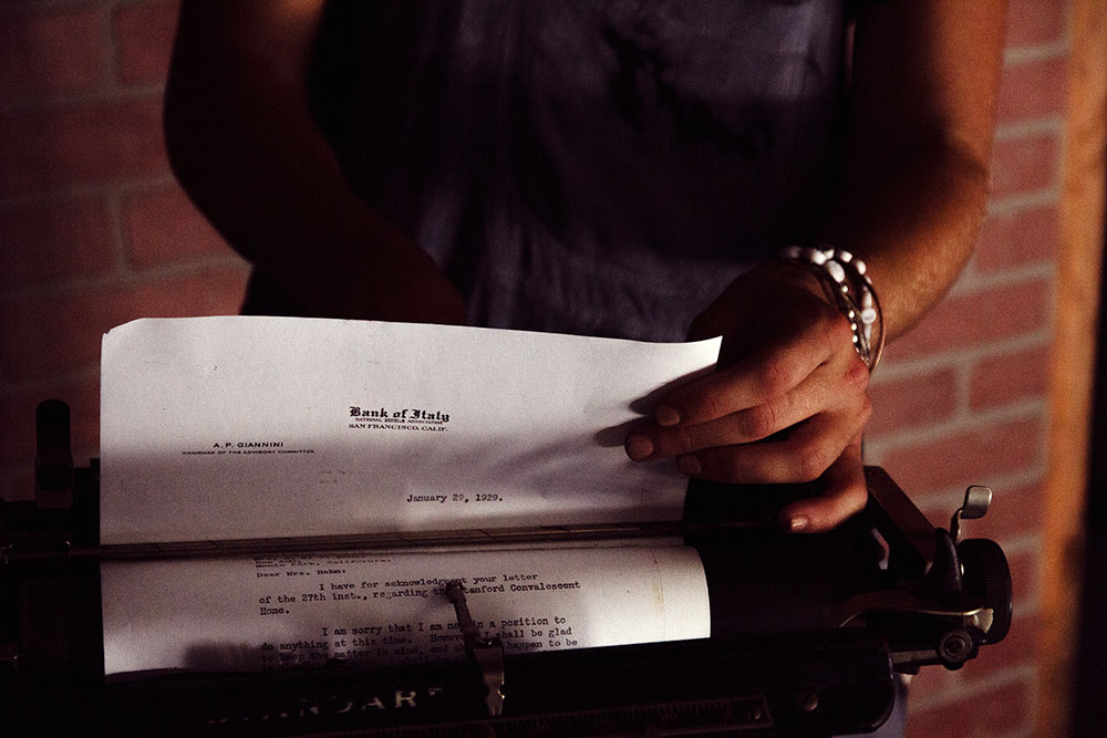 Woman pulling piece of paper out of a typewriter