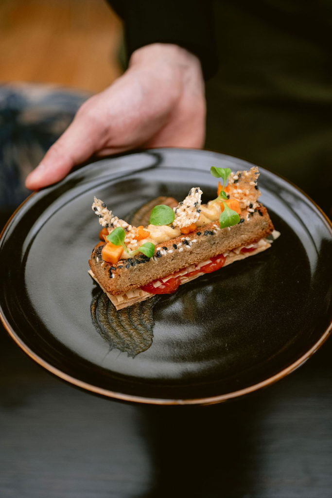 Hand holding a plate with an elaborate dessert
