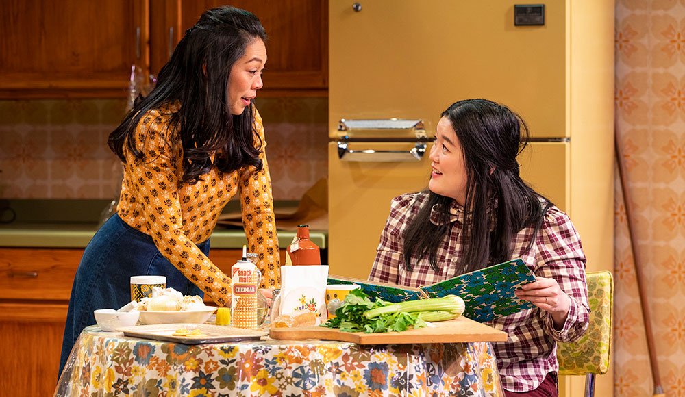 Two women in a kitchen set on a stage