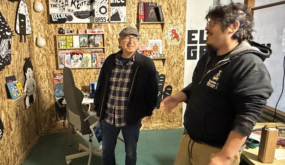 Two men standing in a room and talking