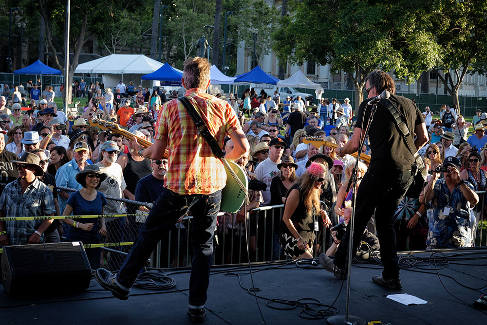 Musicians seen from behind performing on an outside stage