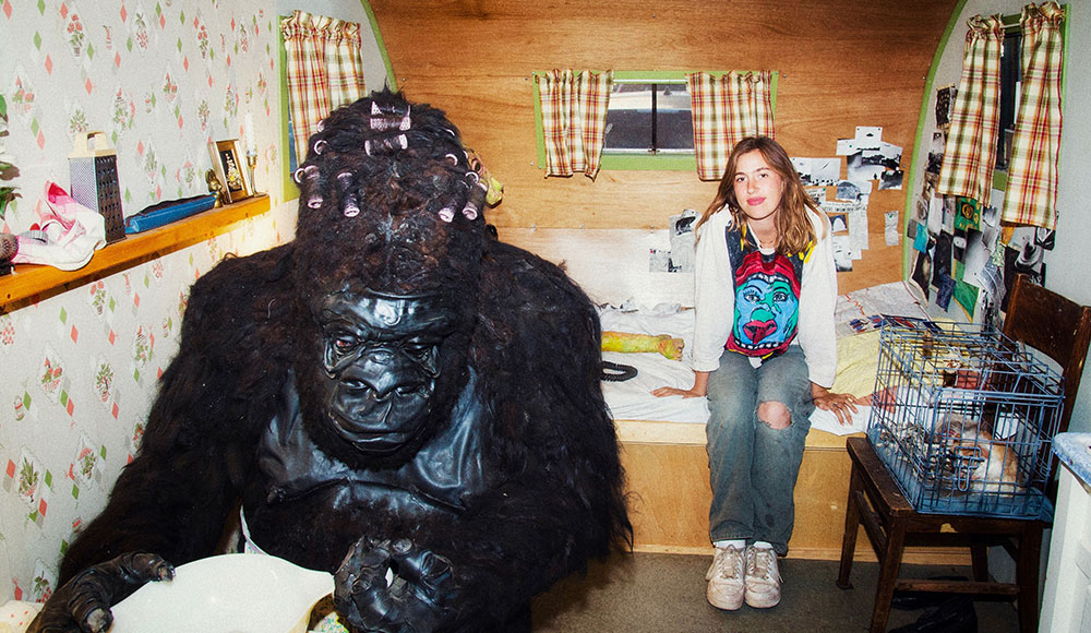 A gorilla made out of llama fur and a woman inside a trailer