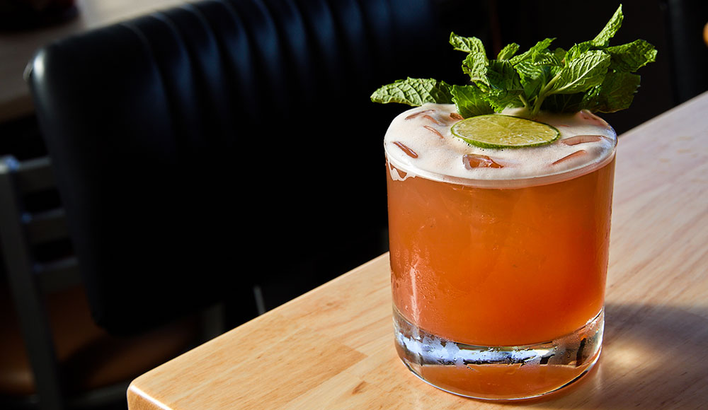 Cocktail with mint garnish sitting on a table