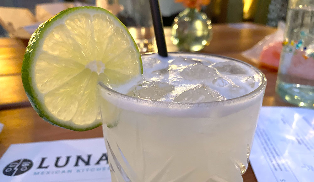 Closeup of a cocktail with a lime garnish