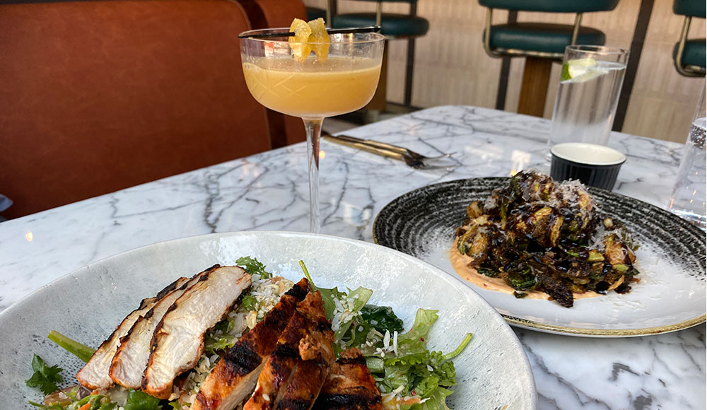 Two plates of food and a drink on a marble tabletop