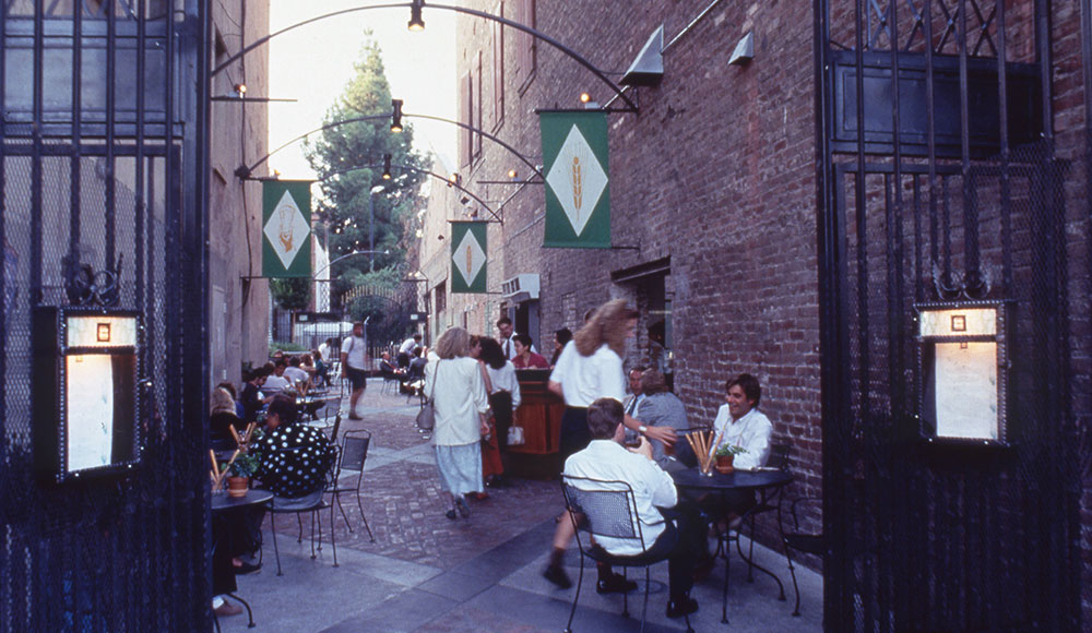 People sittlng on a narrow brick-lined patio