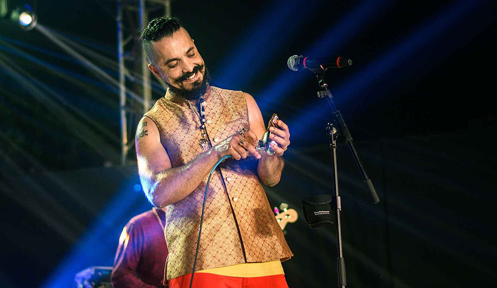 Man holding a harmonica in his hand while he stands on stage
