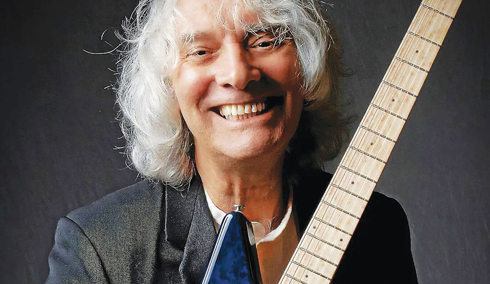 Man smiling and holding a guitar