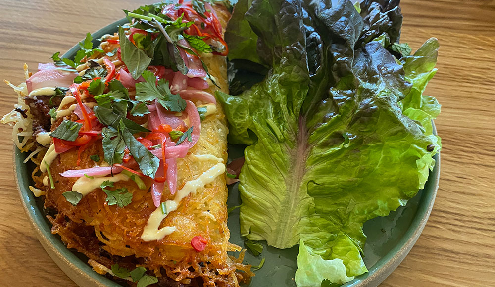 Potato crepe next to large lettuce leaf