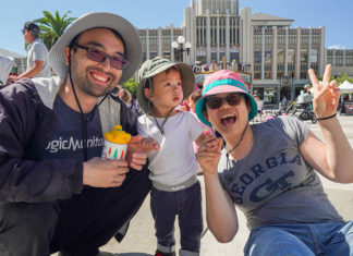 Kid and parents waving at the camera at an outdoor event