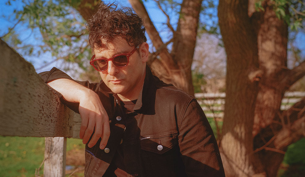 man leaning on a fence under a tree
