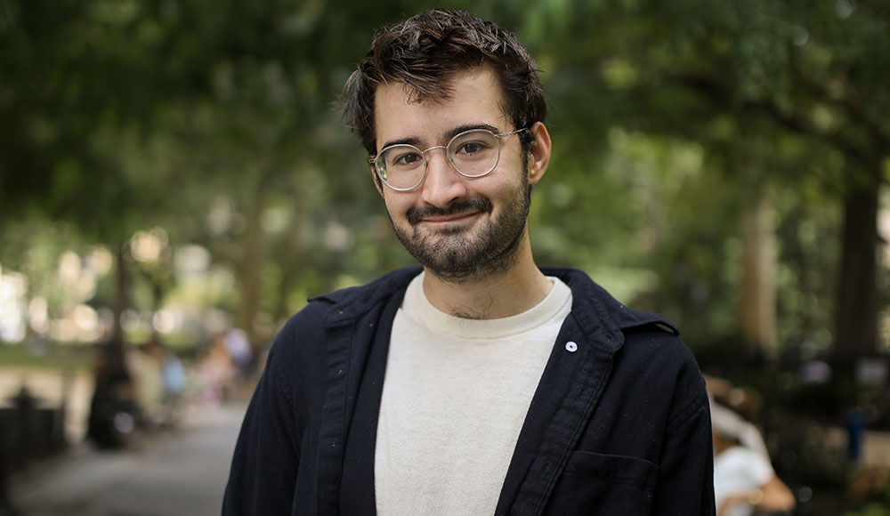 Photo of a man outside, wearing a white t-shirt and black jacket