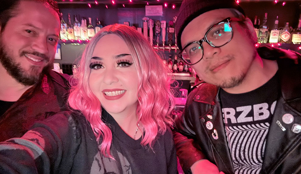 three people posing for a photo inside a nightclub