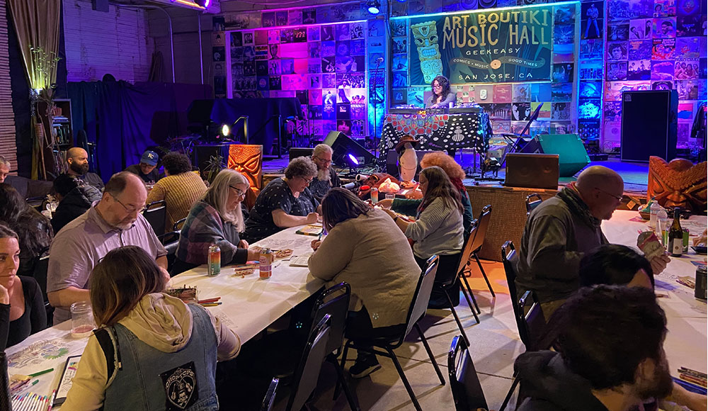 People sitting at long tables in a room with colorful lighting