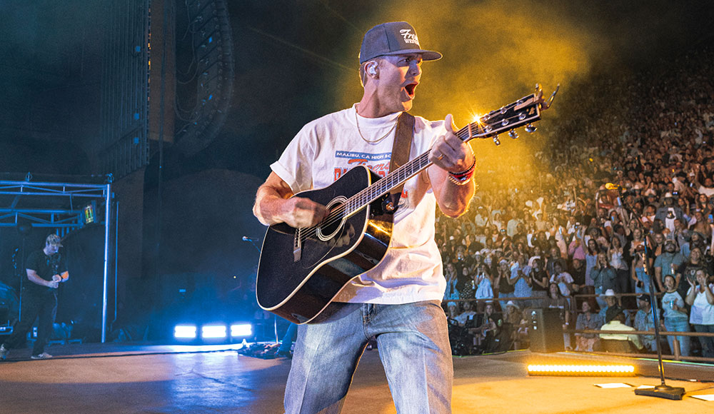 Man playing guitar on a stage with the audience behind him