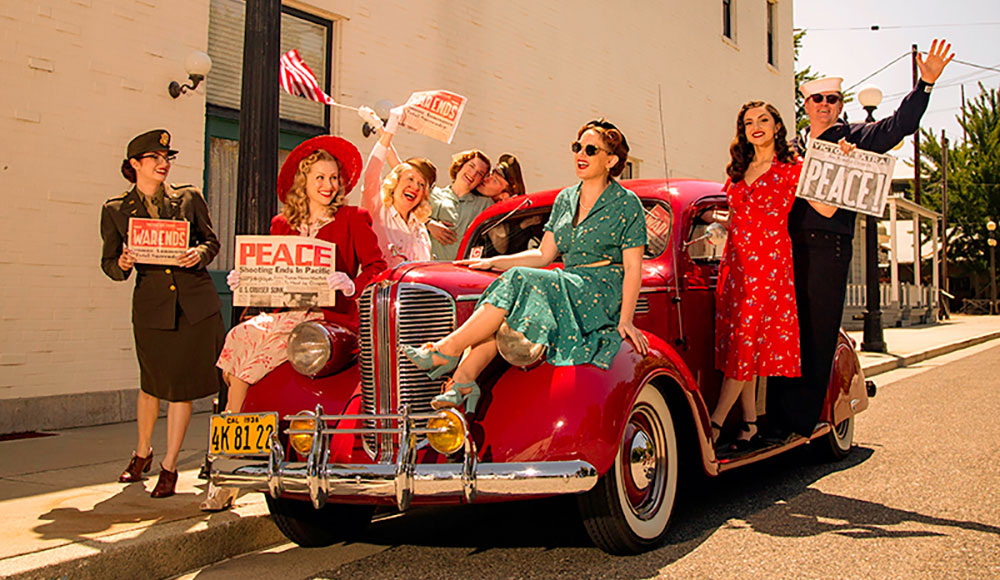 Women dressed in 1940s-style outfits sitting in a vintage car