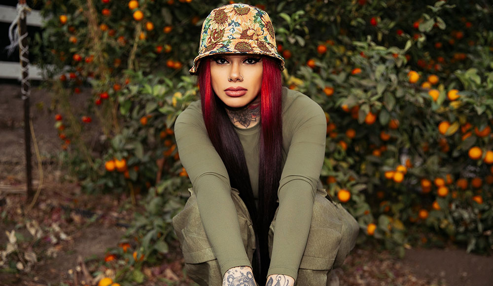 Woman with bright red hair crouching down and staring at the camera