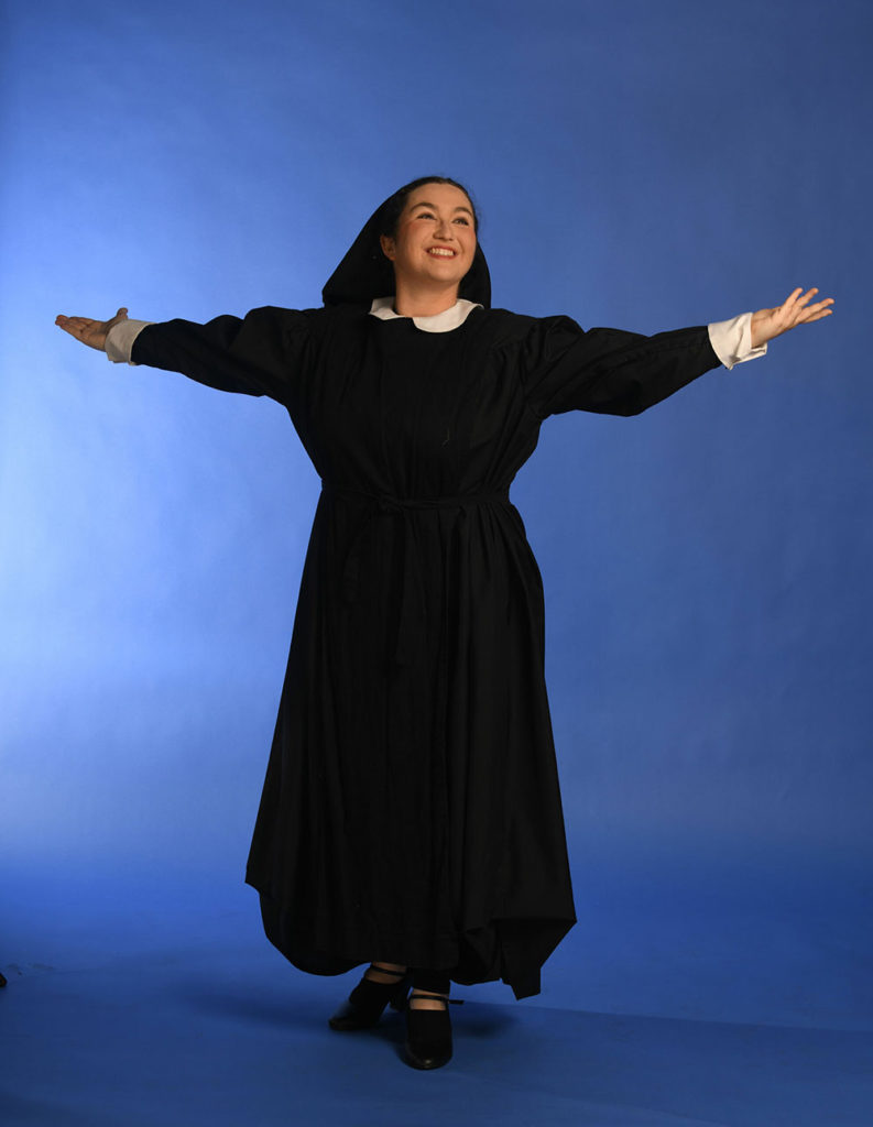 Woman wearing a nun's costume and extending her arms