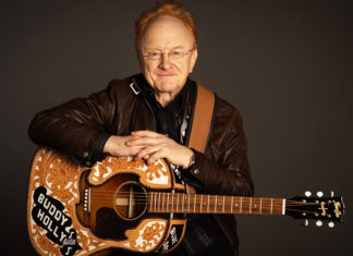 Man sitting down and holding a guitar