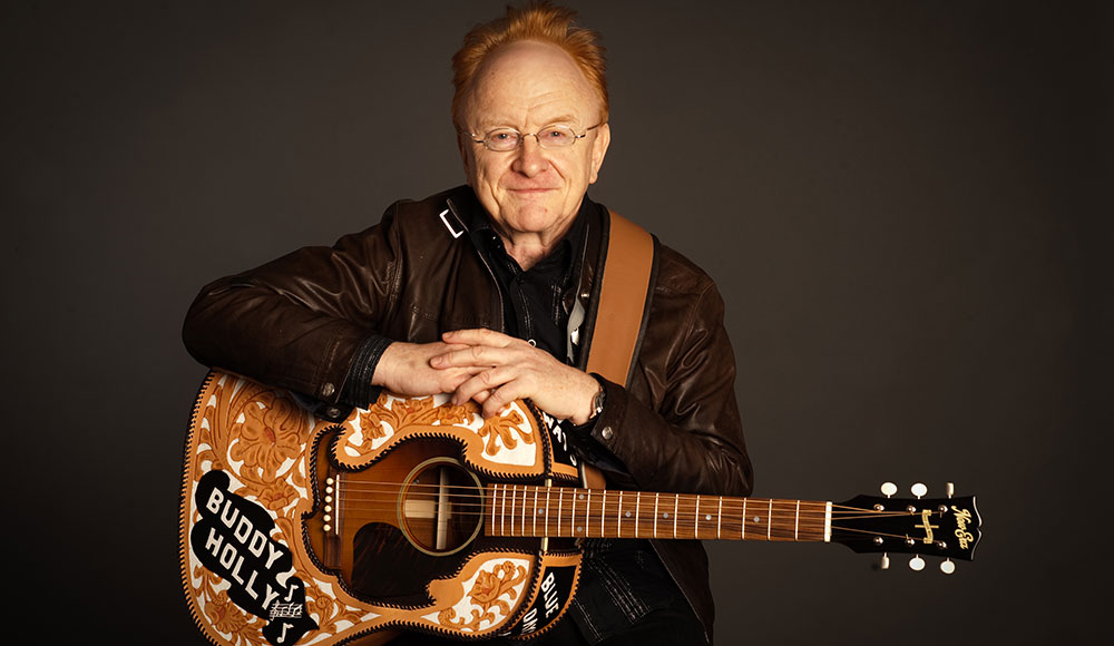 Man sitting down and holding a guitar