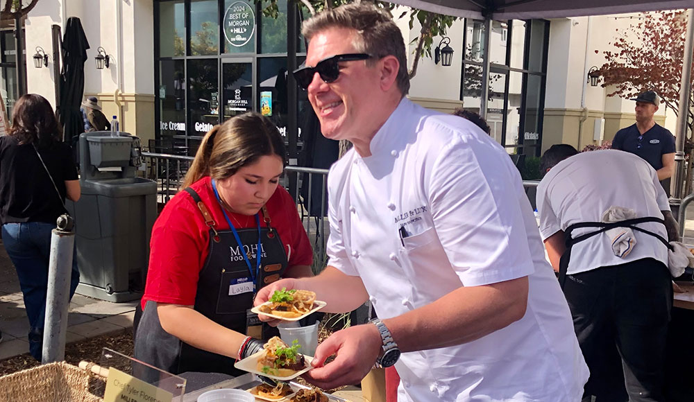 man in chef's whites serving food at an event