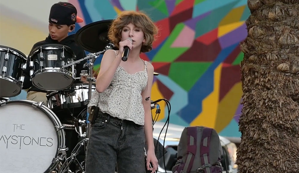 Kids onstage—one singing, one drumming