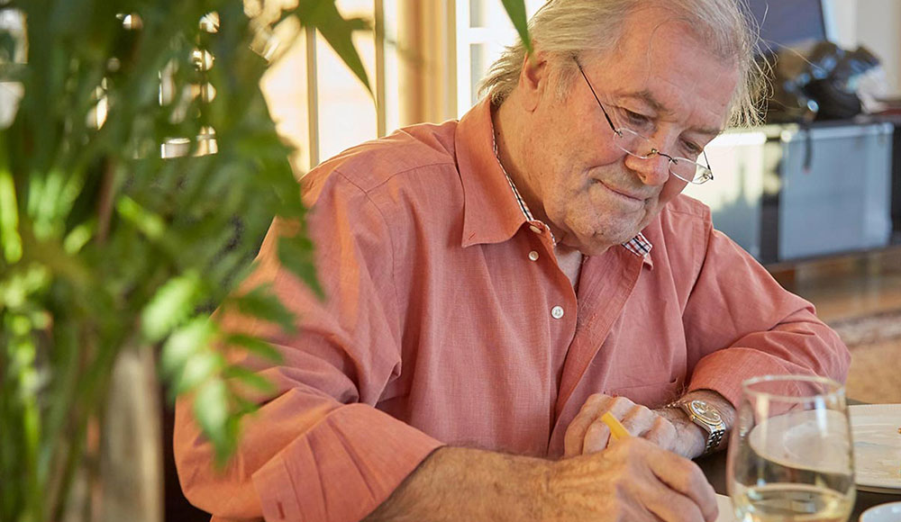 Man sitting in a kitchen or den looking at a book