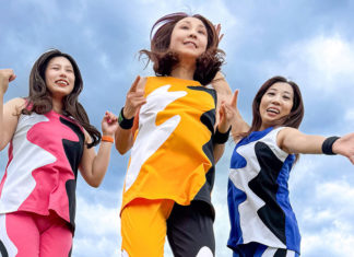 Three women wearing boldly colored pants and matching tops, jumping in the air