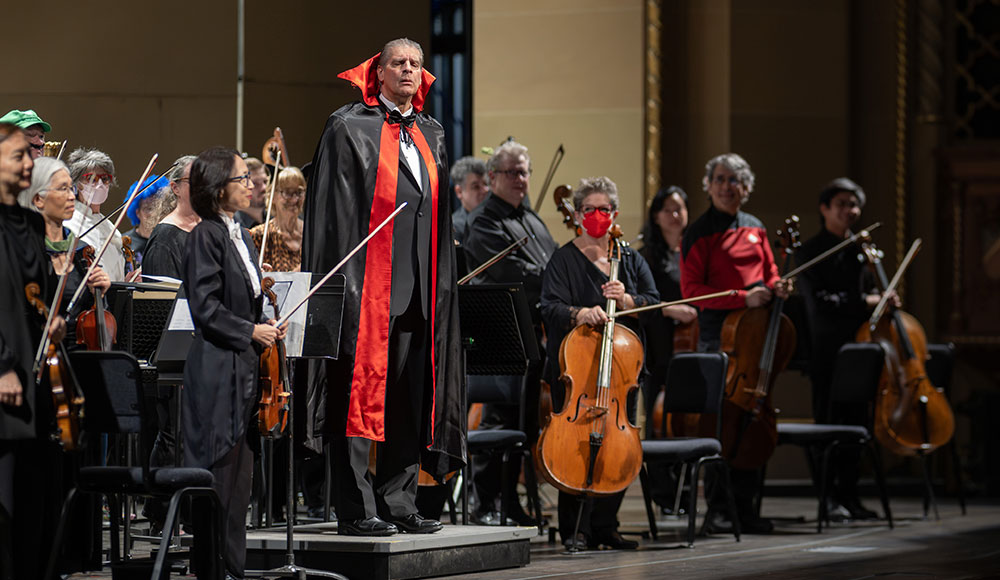Orchestra conductor on stage wearing Dracula costume