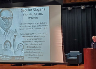 man at podium next to a large slide projection