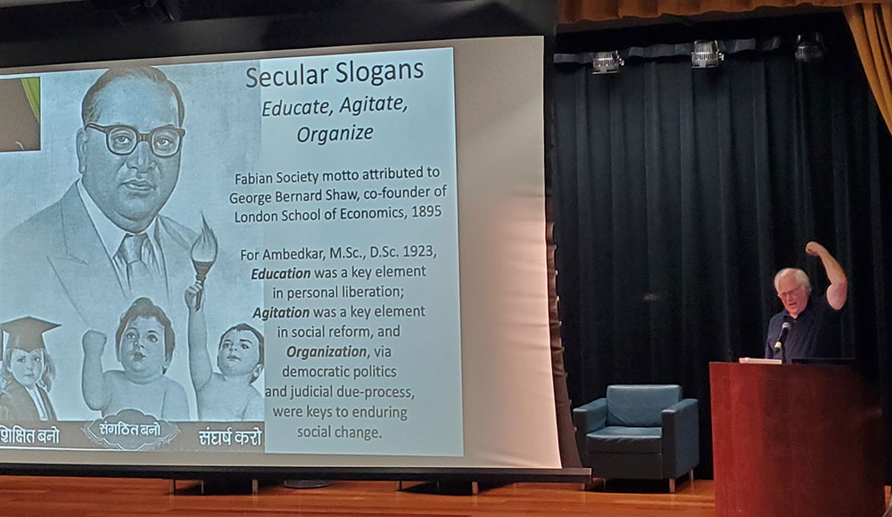 man at podium next to a large slide projection