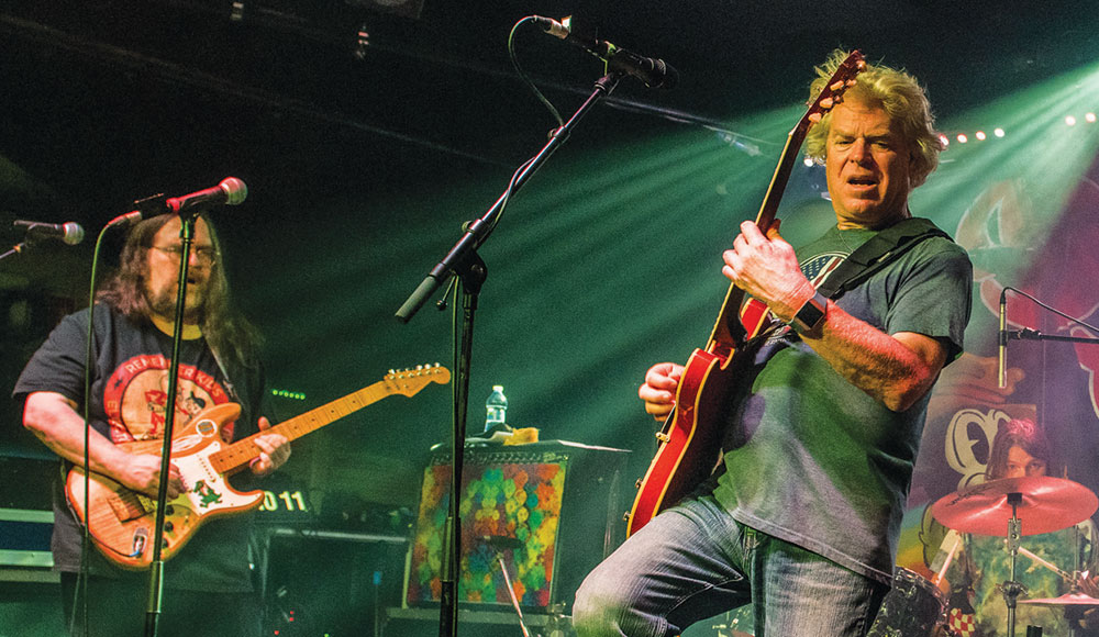 Two men playing electric guitars on a stage