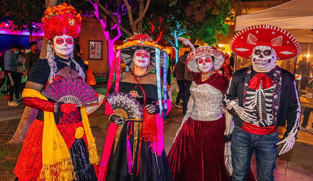 Four people wearing calavera costumes for Day of the Dead