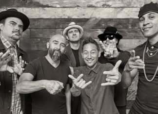 Six membes of a band posing for a black-and-white portrait