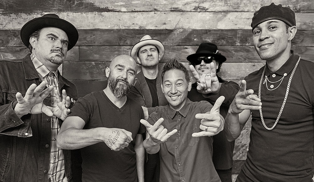 Six membes of a band posing for a black-and-white portrait