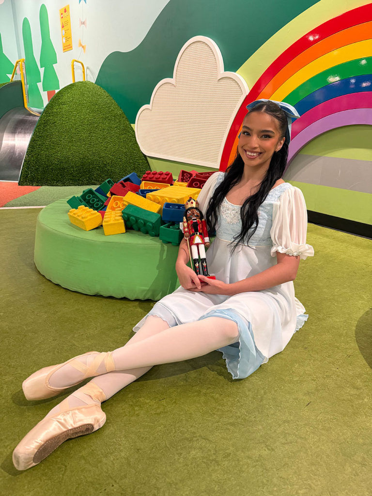 Ballet dancer sitting on the ground next to a pile of LEGOs.